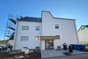 Außenaufnahme der neuen, in hellgrau gehaltenen mit weißen Rändern an den Fenstern versehen Außenfassade.