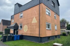 Außenaufnahme der rötlichen und verwitterten Fassade.