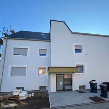 Außenaufnahme der neuen, in hellgrau gehaltenen mit weißen Rändern an den Fenstern versehen Außenfassade.